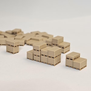 May include: Miniature beige cardboard boxes stacked on small wooden pallets. The boxes are arranged in various configurations, suggesting a warehouse or shipping theme. The boxes are all the same size and colour.