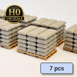 May include: Miniature model of stacked sandbags on wooden pallets. The sandbags are a light beige colour, and the pallets are brown. The image includes a gold and black emblem that reads "HO 1/87 SCALE" and a blue rectangle with the text "7 pcs".