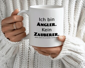 May include: White ceramic mug with a black handle. The mug has black text that reads "Ich bin Angler. Kein Zauberer. Wobei, wenn ich so darüber nachdenke..."