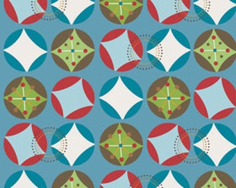 May include: A repeating pattern of colorful circles and diamond shapes on a blue background. The circles contain diamonds, crosses, and other geometric designs in shades of blue, green, red, and white. The pattern is printed on fabric, with a ruler along the bottom showing inches.