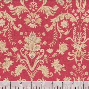May include: Close-up of a red fabric featuring a repeating pattern of beige and off-white floral and scroll designs. The fabric has a textured appearance, and a ruler is visible along the bottom edge, with markings in inches.