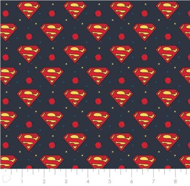May include: A navy blue fabric with a repeating pattern of red Superman logos and small red circles. The fabric has a subtle yellow and white speckled pattern.