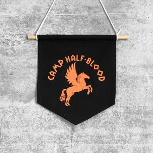 Könnte beinhalten: Schwarzer Wandbehang aus Canvas mit dem Text "Camp Half-Blood" in orangefarbener Schrift. Ein stilisiertes orangefarbenes Pegasus befindet sich in der Mitte des Banners.