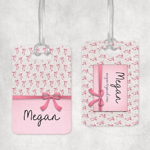 Op de afbeelding: Twee roze bagagelabels met doorzichtige plastic lussen. De labels hebben een witte achtergrond met een patroon van roze strikken. Eén label heeft de naam "Megan" in cursief en een roze strik. Het andere label heeft de naam "Megan" en een e-mailadres.
