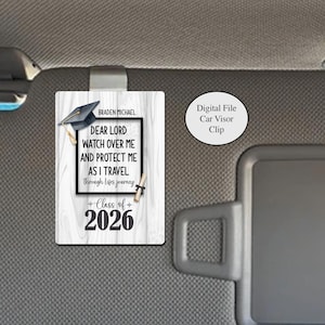 Könnte beinhalten: Ein rechteckiger Sonnenblendenclip für Autos mit einem Abschluss-Thema. Der Clip zeigt eine schwarze Abschlusskappe, eine Schriftrolle und den Text "DEAR LORD WATCH OVER ME AND PROTECT ME AS I TRAVEL through lifes journey" und "Class of 2026".