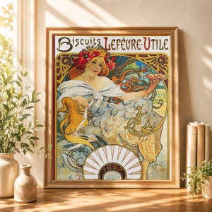 May include: A framed art print featuring the 1897 Biscuits Lefèvre-Utile advertisement. The illustration depicts a woman with flowing hair adorned with red poppies, wearing a white shawl and patterned dress, holding a small plate of biscuits.