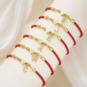 Pulsera de acero inoxidable dorado para mujer con dije de corazón y letra inicial de la A a la Z. Cordón rojo ajustable de la suerte. Joyería elegante y refinada.