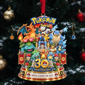 Könnte beinhalten: Ein Pokémon 30-Jahre-Jubiläums-Ornament mit Ash Ketchum, Pikachu, Glurak, Turtok, Bisaflor und weiteren Figuren. Der Sockel zeigt den Text '30th ANNIVERSARY' und 'GOTTA CATCH 'EM ALL!' mit einem roten Band zum Aufhängen am Weihnachtsbaum.