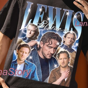 Puede incluir: Camiseta unisex negra con un gráfico de Lewis Pullman y el texto "LEWIS Pullman". El diseño tiene una estética vintage, con múltiples imágenes del actor. Las palabras "UNISEX T-SHIRT" están en la parte superior.