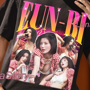 May include: Black unisex t-shirt featuring a graphic of a group of women in red and white checkered tops. The shirt has the text "FUN-BI" in pink and yellow, with the Lana Story logo.