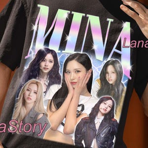 May include: Black unisex t-shirt featuring a graphic of the word "MINA" in a retro font with a photo collage of women. The shirt also has the text "UNISEX T-SHIRT" and "Lana Story".
