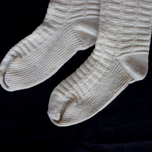 May include: A pair of white knitted socks with a ribbed texture.