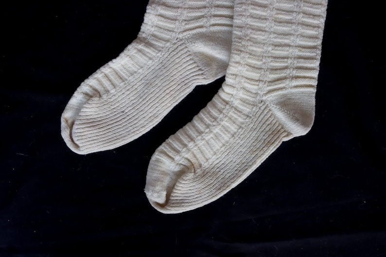 May include: A pair of white knitted socks with a ribbed texture.
