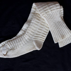 May include: A pair of white knitted knee-high socks with a ribbed texture.