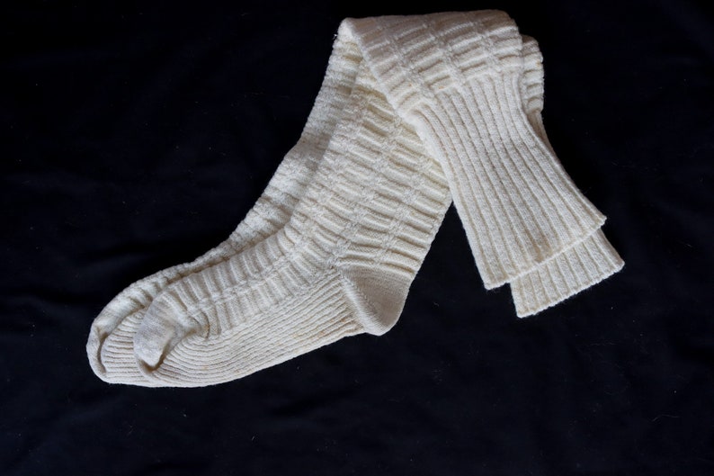 May include: A pair of white knitted knee-high socks with a ribbed texture.