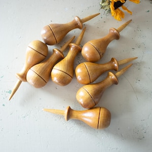 May include: A set of three ceramic mugs with a speckled, matte finish. The mugs are in shades of cream, light gray, and dark gray. Each mug has a simple, minimalist design and a rounded handle.