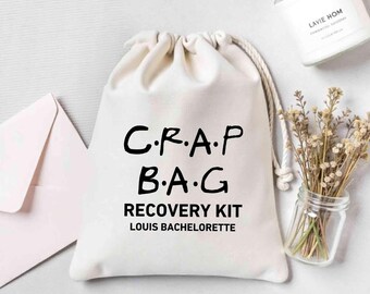 May include: A white drawstring bag with the text "C.R.A.P B.A.G RECOVERY KIT LOUIS BACHELORETTE" printed in black.