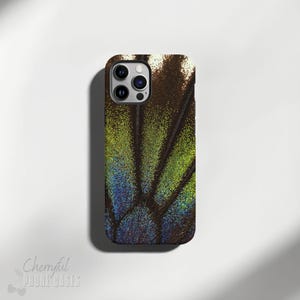 May include: A phone case with a close-up image of a butterfly wing. The wing is a dark brown color with green and blue iridescent patterns.
