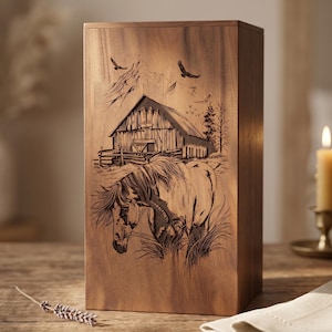Op de afbeelding: Een houten kist met een gedetailleerde gravure van een paard, schuur, bergen en vogels. Het kunstwerk is in het hout geëtst, wat een rustieke en natuurlijke uitstraling creëert. De doos is rechthoekig en staat rechtop.
