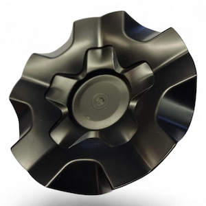 以下が含まれることがあります： 中央に円形の要素がある、濃い灰色の歯車型のオブジェクト。オブジェクトは金属的な光沢があり、複雑な多層設計です。歯車のような構造は、湾曲したエッジと中央のハブを備えています。