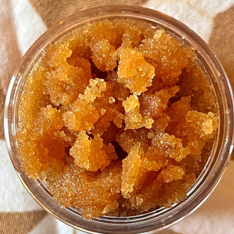 top view of a clear jar with brown sugar facial scrub, Raw Olive, moisturing and exfoliating natural scrub