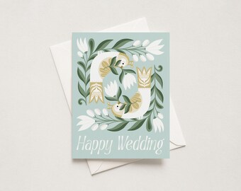 May include: A light blue greeting card with a white envelope featuring a symmetrical illustration of two white birds with gold accents, surrounded by green leaves and white flowers, with the white text Happy Wedding printed at the bottom.