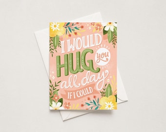 May include: A rectangular greeting card with a soft pink background featuring the text I WOULD HUG you all day IF I COULD in green and white lettering. The design is decorated with colorful illustrations of yellow and white flowers and green leaves.