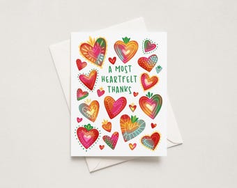 May include: A white greeting card featuring a colorful array of illustrated hearts in various sizes, patterns, and gradients of red, orange, yellow, green, and blue. The text in the center reads A MOST HEARTFELT THANKS in green capital letters.