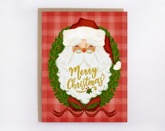 May include: A Christmas greeting card featuring Santa Claus inside a green wreath with a red bow. The card has a red plaid background and the words "Merry Christmas" in gold script.