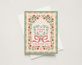 May include: A rectangular greeting card with a scalloped border in sage green and pale pink. The design features a central heart-shaped wreath of green leaves and red flowers, a red ribbon bow, and the text WISHING YOU EVERLASTING LOVE.