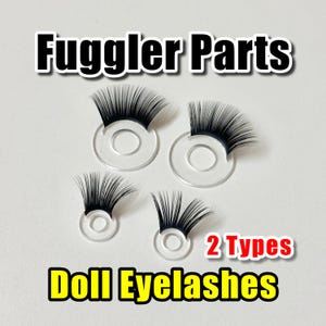 May include: Four sets of doll eyelashes with black lashes attached to clear, circular bases. The text "Fuggler Parts" and "Doll Eyelashes" are displayed above and below the eyelashes, respectively. The text "2 Types" is also visible.