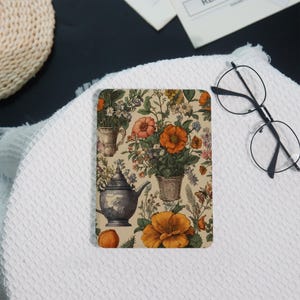 May include: A rectangular floral design with orange and pink flowers, a teapot, and plants in pots on a beige background. The image also includes a white towel, a woven basket, and black-framed glasses. The design has a vintage aesthetic.