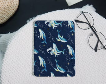 May include: A rectangular coaster with a navy blue background featuring a watercolor pattern of whales, white splashes, and small yellow stars. The whales are blue and yellow.