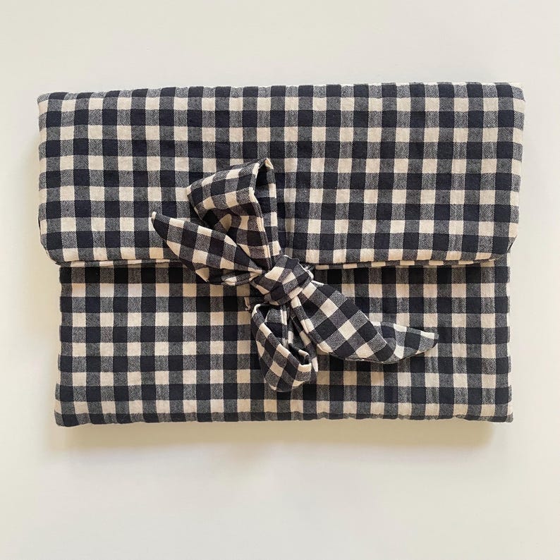 Puede incluir: Un bolso de mano con estampado de cuadros vichy en blanco y negro con cierre de lazo a juego. La tela es un material suave y tejido. El bolso de mano est&aacute; doblado y asegurado con un lazo grande.