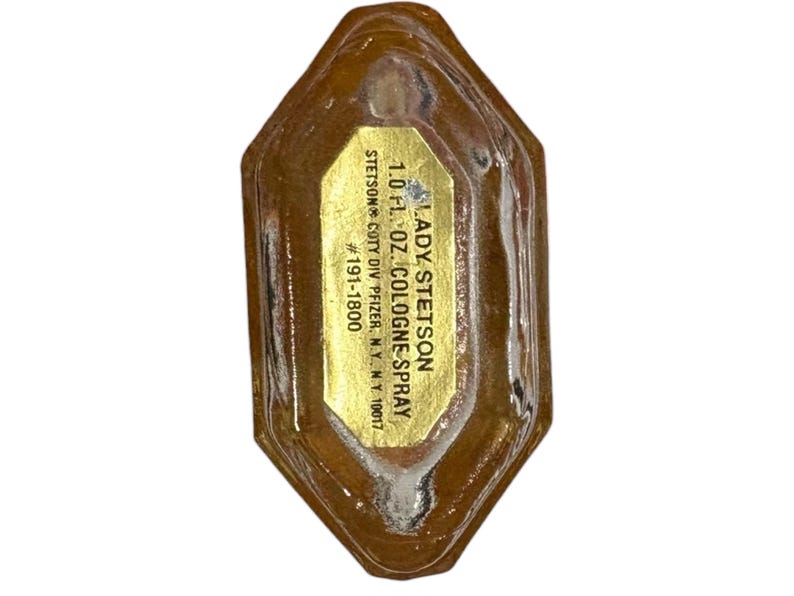 Peut inclure: Une bouteille de parfum Lady Stetson vintage. La bouteille est de couleur ambre clair avec une &eacute;tiquette dor&eacute;e. L'&eacute;tiquette indique "LADY STETSON 1.0 fl. oz. COLOGNE SPRAY". La bouteille porte le num&eacute;ro #191-1800.