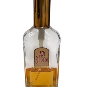 Peut inclure: Flacon de parfum en verre transparent avec un bouchon dor&eacute; et une &eacute;tiquette "LADY STETSON". Le flacon contient un liquide ambr&eacute; clair. Le design est classique et vintage.
