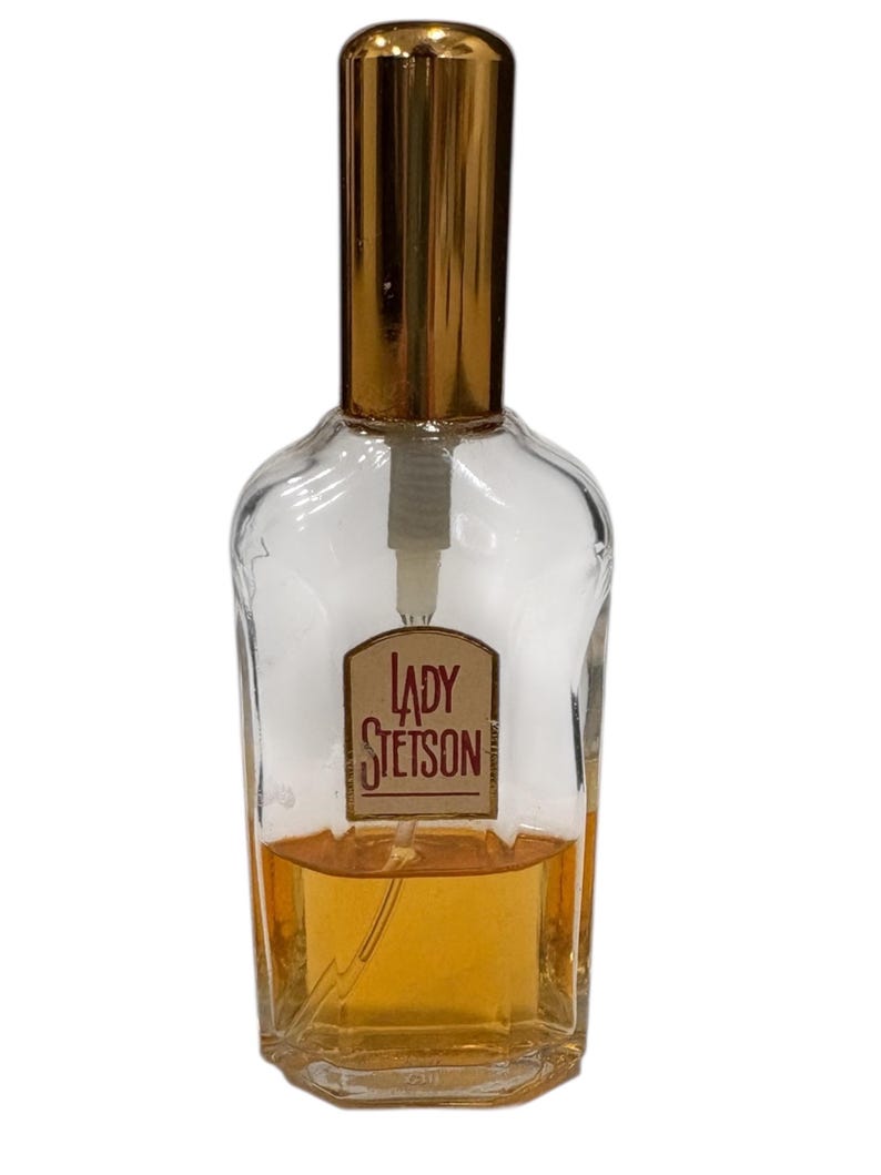Peut inclure: Flacon de parfum en verre transparent avec un bouchon dor&eacute; et une &eacute;tiquette "LADY STETSON". Le flacon contient un liquide ambr&eacute; clair. Le design est classique et vintage.