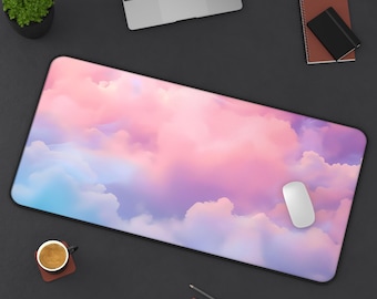 May include: A rectangular mouse pad with a dreamy cloudscape design in shades of pink, purple, and blue. A white computer mouse rests on the pad. Other items on the dark surface include a laptop, a small plant, and a cup of coffee.