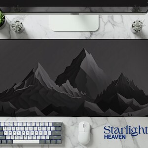 Puede incluir: Alfombrilla de escritorio rectangular negra y gris con un diseño de cordillera. Hay un teclado y un ratón en la superficie de la alfombrilla. El texto "Starlight Heaven" es visible.