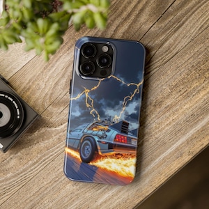 May include: A black phone case with a graphic of a DeLorean time machine driving through a stormy sky with lightning bolts. The car is on fire and the text "OUTATIME" is visible on the back of the car.