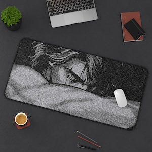 May include: Black and white rectangular mousepad featuring a detailed illustration of a person's face. The mousepad is surrounded by a black border. A white mouse is on the right side of the mousepad.
