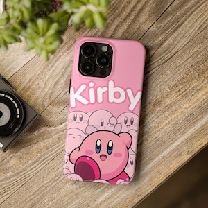 May include: Pink phone case with a pink Kirby character and the word "Kirby" in white letters.