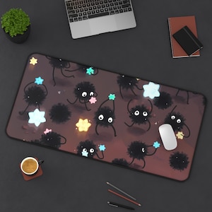 May include: A brown mouse pad with a repeating pattern of black fuzzy creatures holding stars. The stars are in various colors, including blue, green, pink, and yellow.