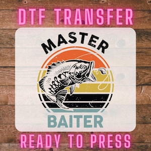 May include: A DTF transfer design featuring a fish illustration with the words "MASTER BAITER" in black, set against a retro sunset design. The words "DTF TRANSFER" and "READY TO PRESS" are in pink.