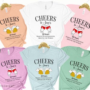 May include: Five different colored t-shirts with the text "CHEERS to Jane's 21 Years MAKING POOR DESICIONS AROUND THE WORLD" and a graphic of either a beer mug or a wine glass.