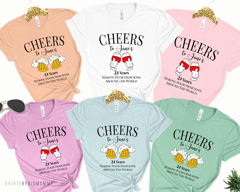 May include: Five different colored t-shirts with the text "CHEERS to Jane's 21 Years MAKING POOR DESICIONS AROUND THE WORLD" and a graphic of either a beer mug or a wine glass.