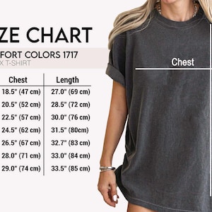 May include: Size chart for a unisex t-shirt, with chest and length measurements in inches and centimeters. The chart includes sizes S, M, L, XL, 2XL, 3XL, and 4XL. The model is wearing a dark gray t-shirt.