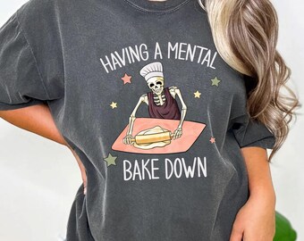May include: A dark gray t-shirt with a skeleton rolling out dough and the text "Having a mental bake down".