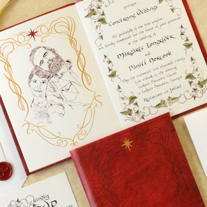 Może przedstawiać: Zestaw zaproszeń ślubnych z czerwoną, skórzaną zaproszeniem w stylu książki, złotymi akcentami i wzorem gwiazdy. Zestaw zawiera kartę RSVP, koperty i pieczęć woskową. Tekst zaproszenia jest w eleganckim skrypcie.