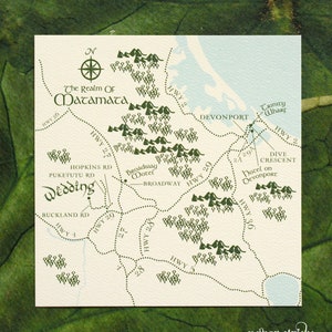 Op de afbeelding: Een handgetekend kaartje van Matamata, Nieuw-Zeeland, met een groen-wit kleurenschema. De kaart toont de locatie van de "Wedding" en het "Broadway Motel" met de tekst "The Realm of Matamata" bovenaan.